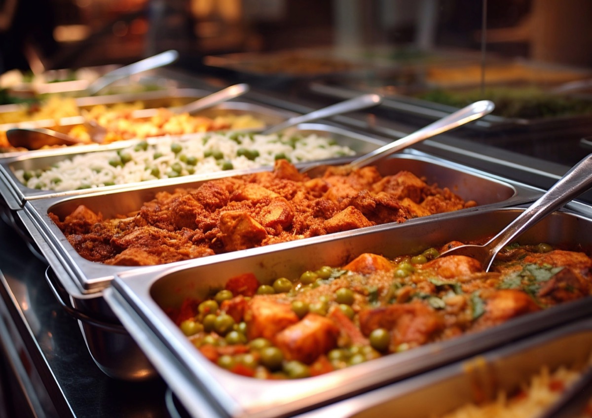Close-up buffet trays of curries and rice set out for a celebration