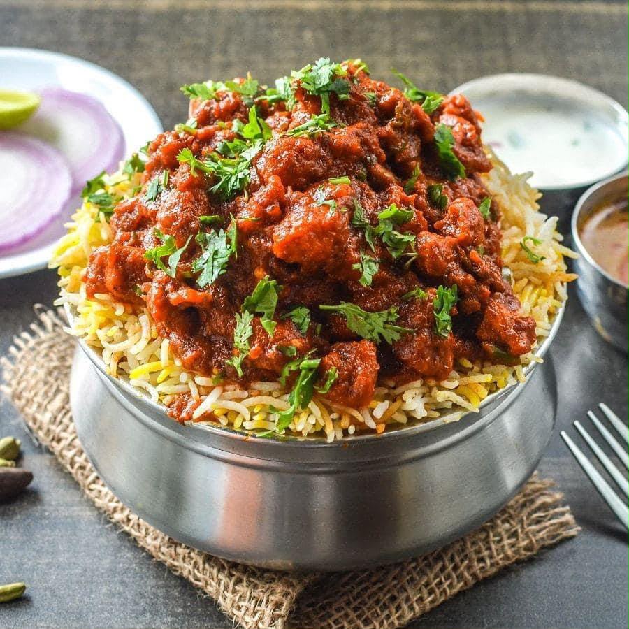 A generous bowl of mutton biryani topped with fresh coriander