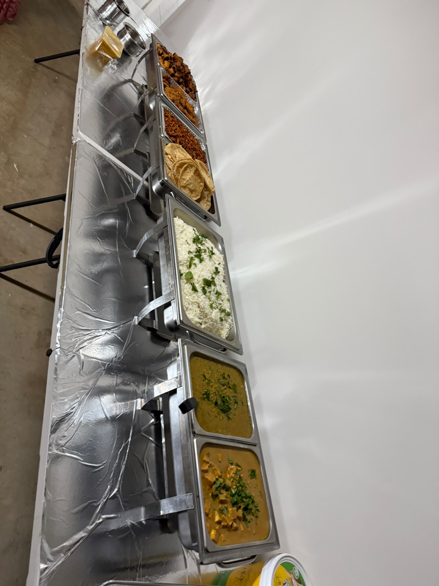 Buffet chafing dishes with dal, rice, papad and curries laid out for catering