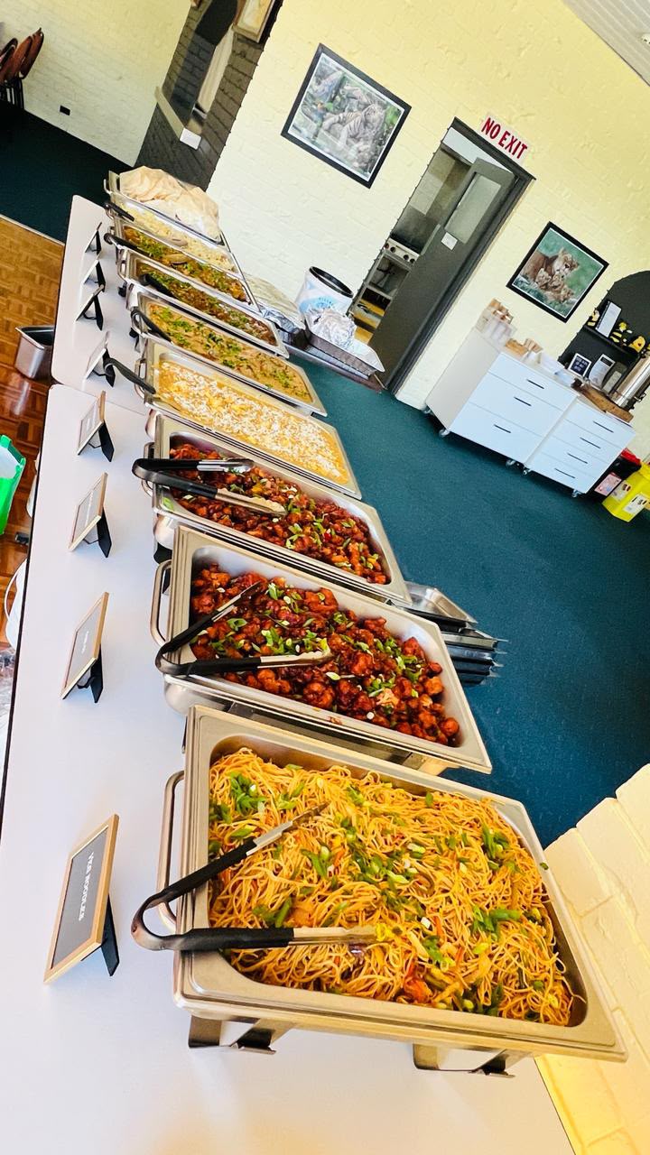 A catering spread of noodles, gobi manchurian and mixed curries